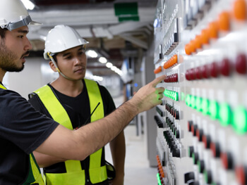 Workers inspecting an electrical panel at a plant in Colombia.