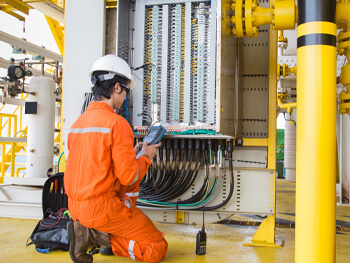 Worker completing electrical maintenance in an industrial setting.